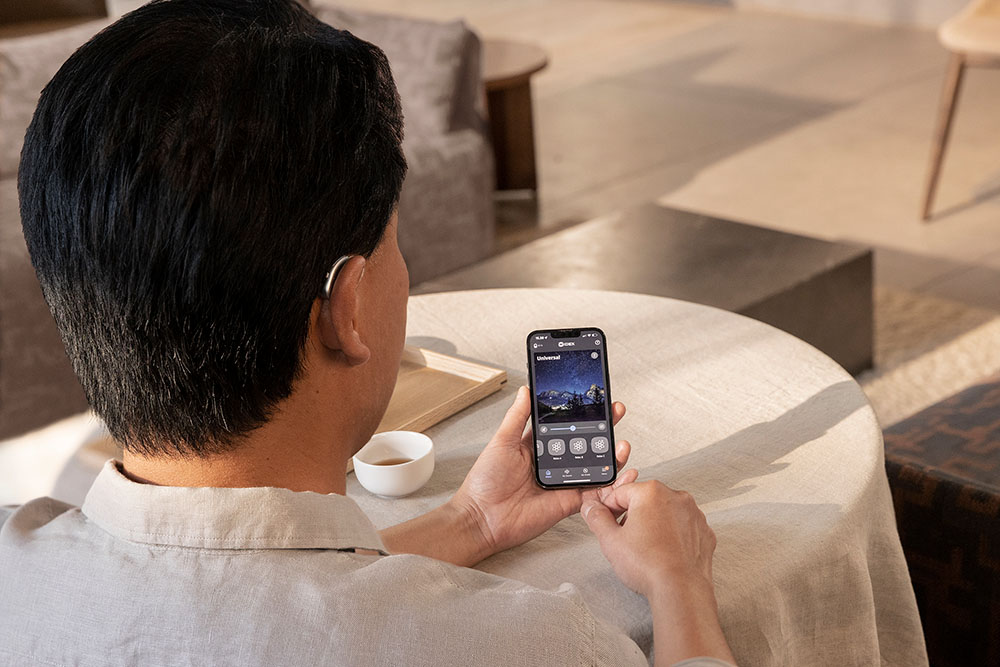 man with hearing aid using a smartphone