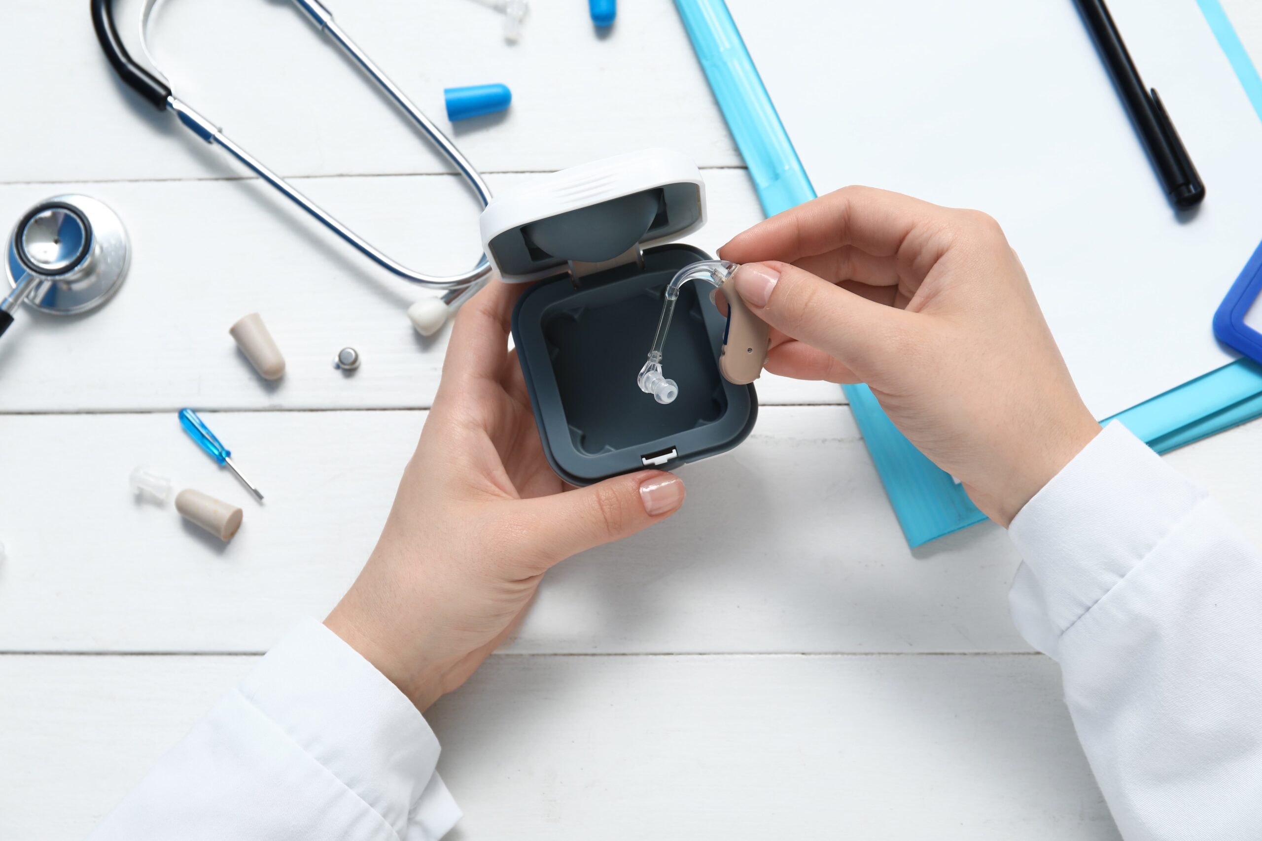 Hands of female doctor with hearing aids.